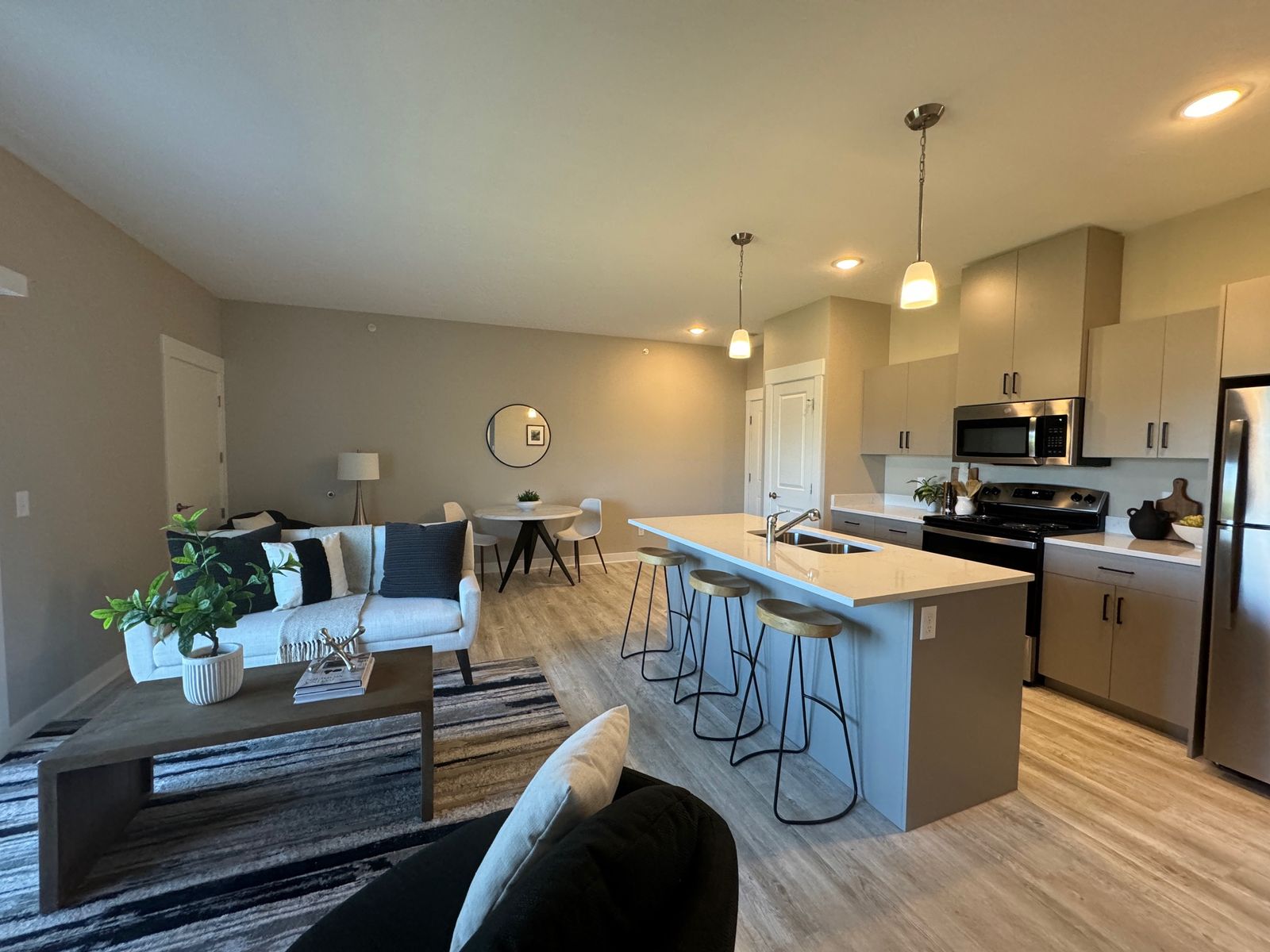 Open kitchen and living room with quartz island, stainless appliances and plank flooring